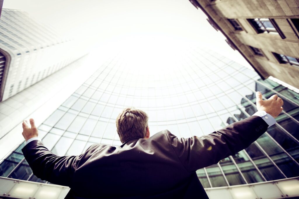 A picture of a man standing in front of a building with his hands raised.