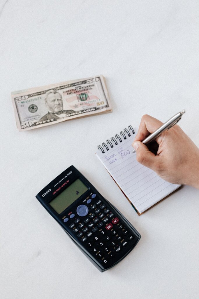 A picture of a person calculating and writing down loan and tax amounts