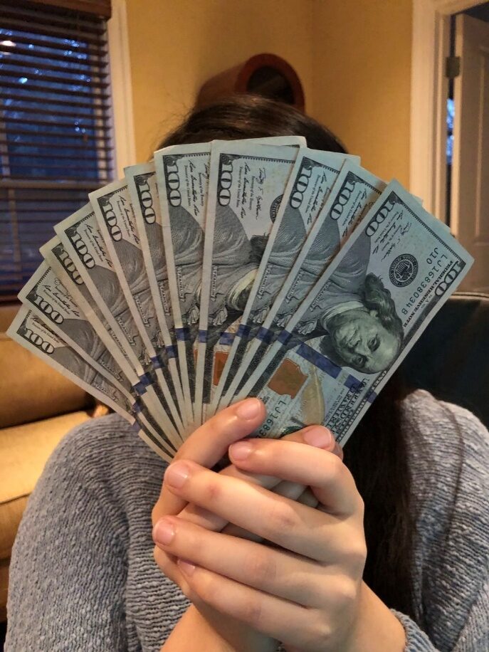 A person holding a set of hundred-dollar notes