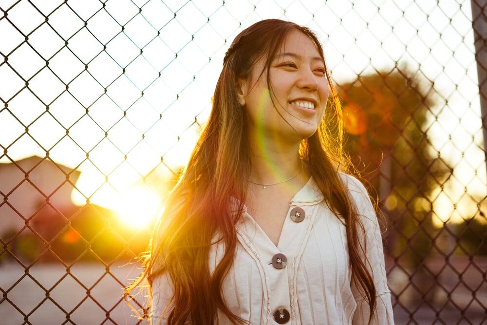 A woman smiling with the sun behind her