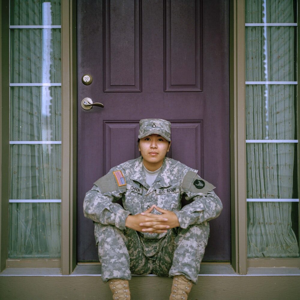 A military service member sitting at the front door of a house
