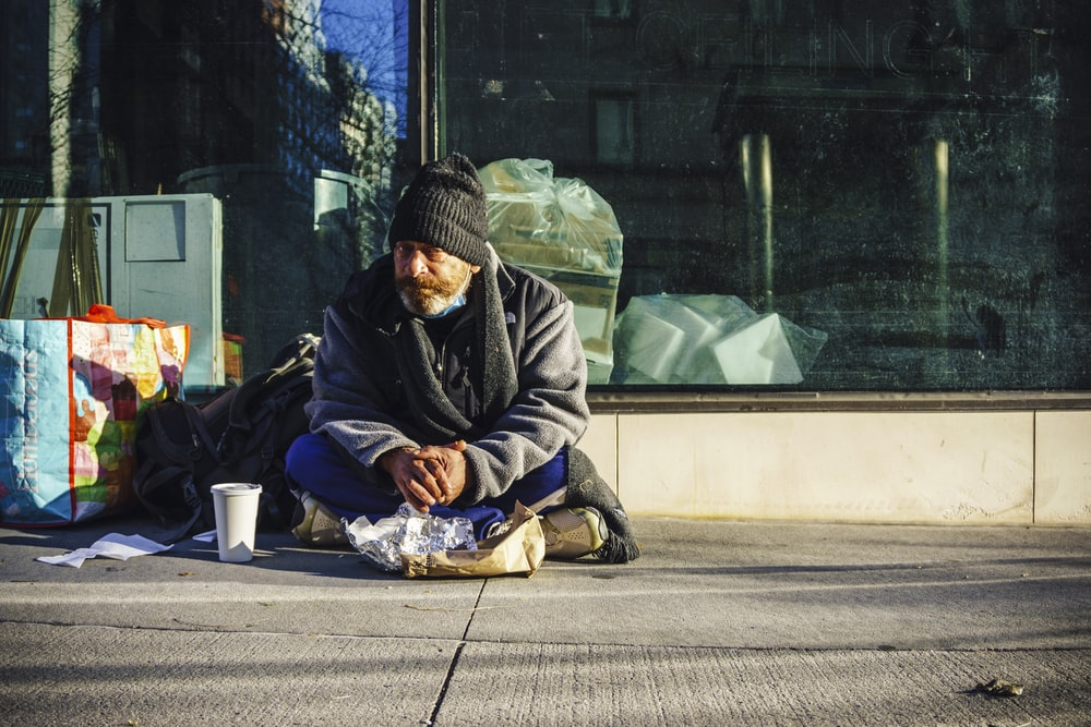 A homeless man sitting outside a building