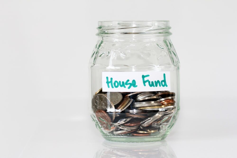 A jar labeled ‘house fund’ with coins inside