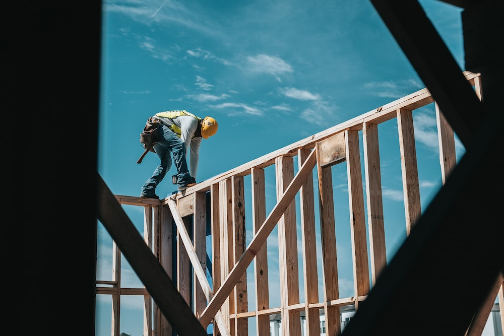 A construction worker standing on wooden beams surrounding a home