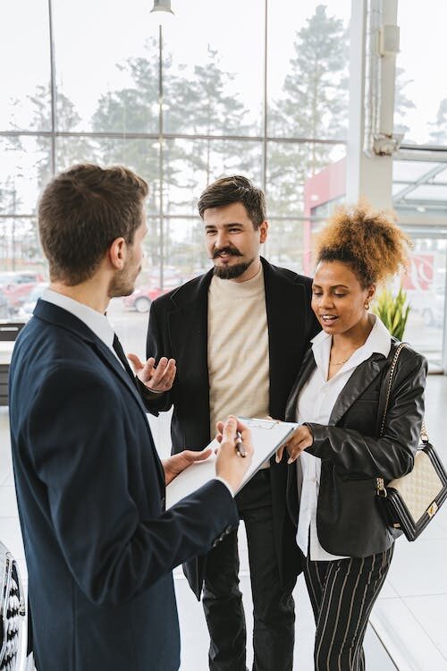 man in a suit holding a clipboard while talking to a couple